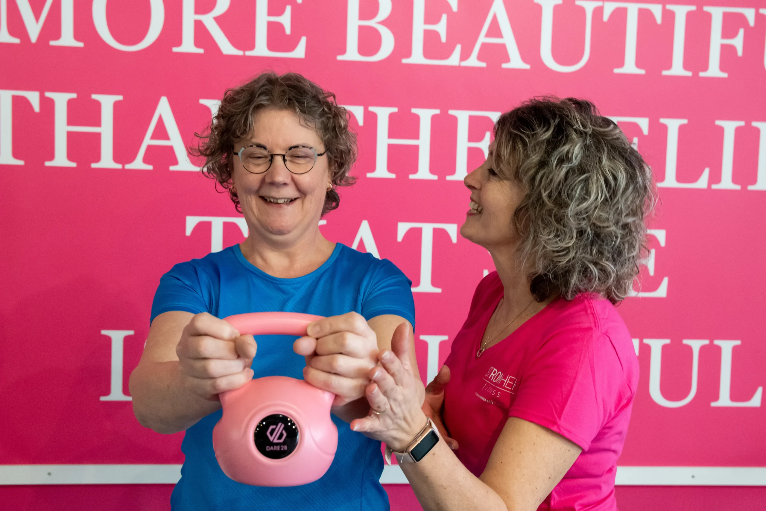 Vrouw voert een halteroefening uit met een roze kettlebel met de hulp van een personal coach in StrongHer fitness Hardinxveld